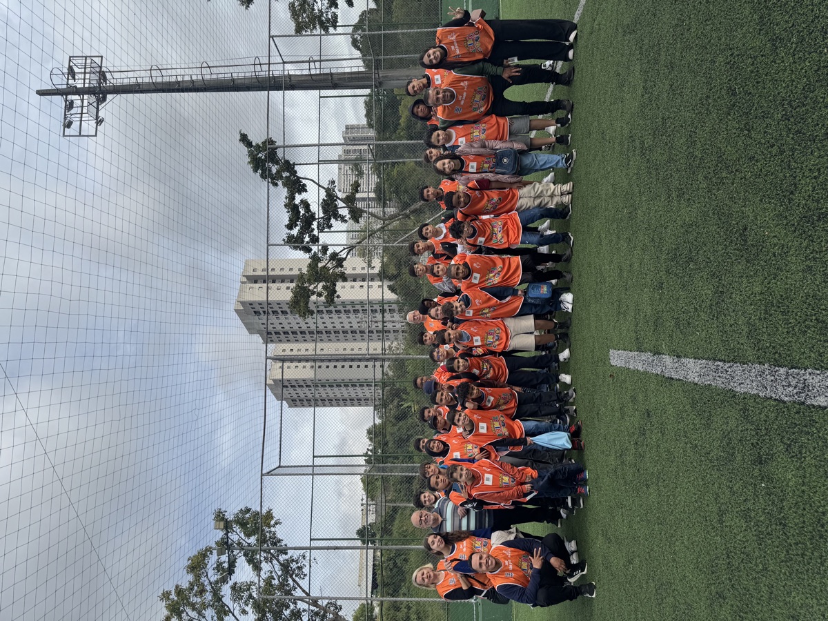 Grupo de crianças e educadores em coletes laranja durante ação no território.