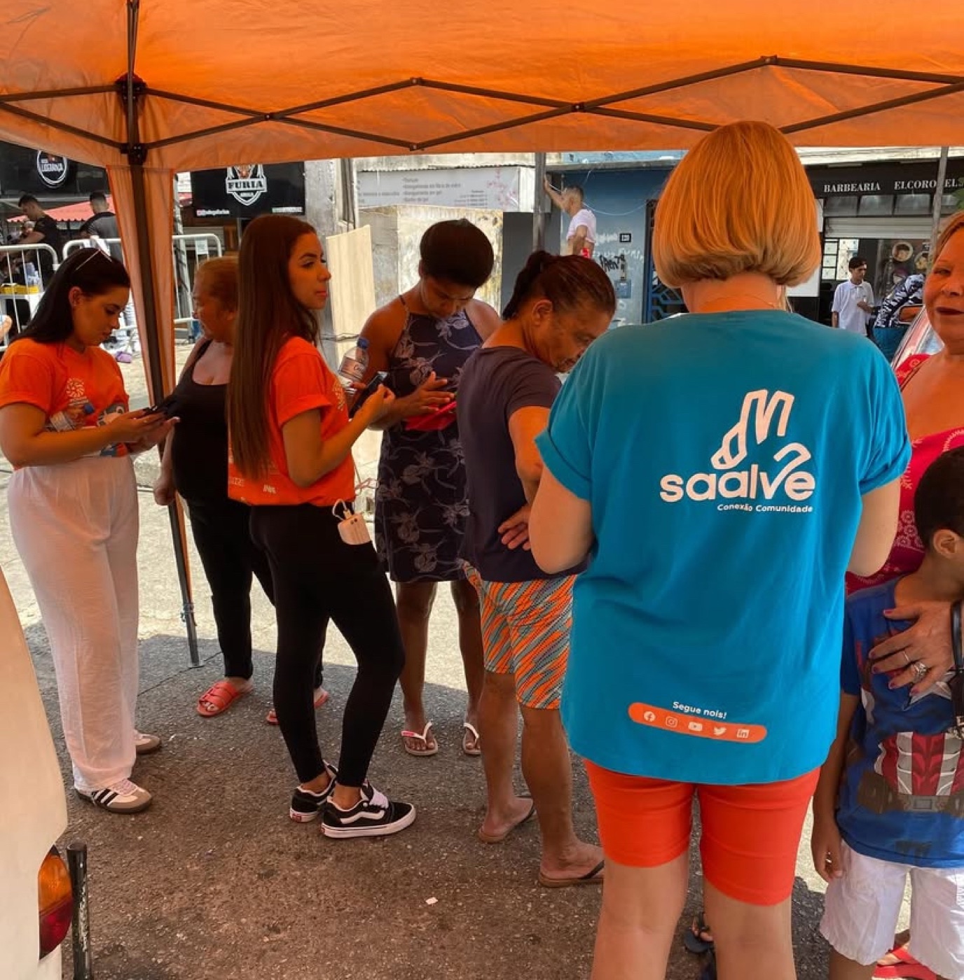Equipe da SAALVE atendendo moradores sob a tenda de uma ação na comunidade.